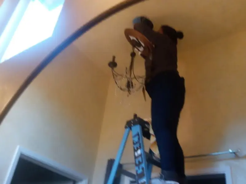 Electrician installing a chandelier in a Chicopee residence